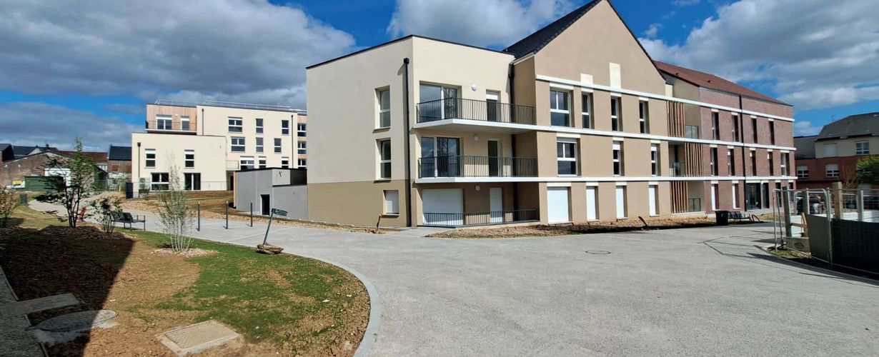 Une vue de plusieurs bâtiments entourés d'une voie piétonne. On peut voir des morceaux de pelouse qui sont en pousse. 